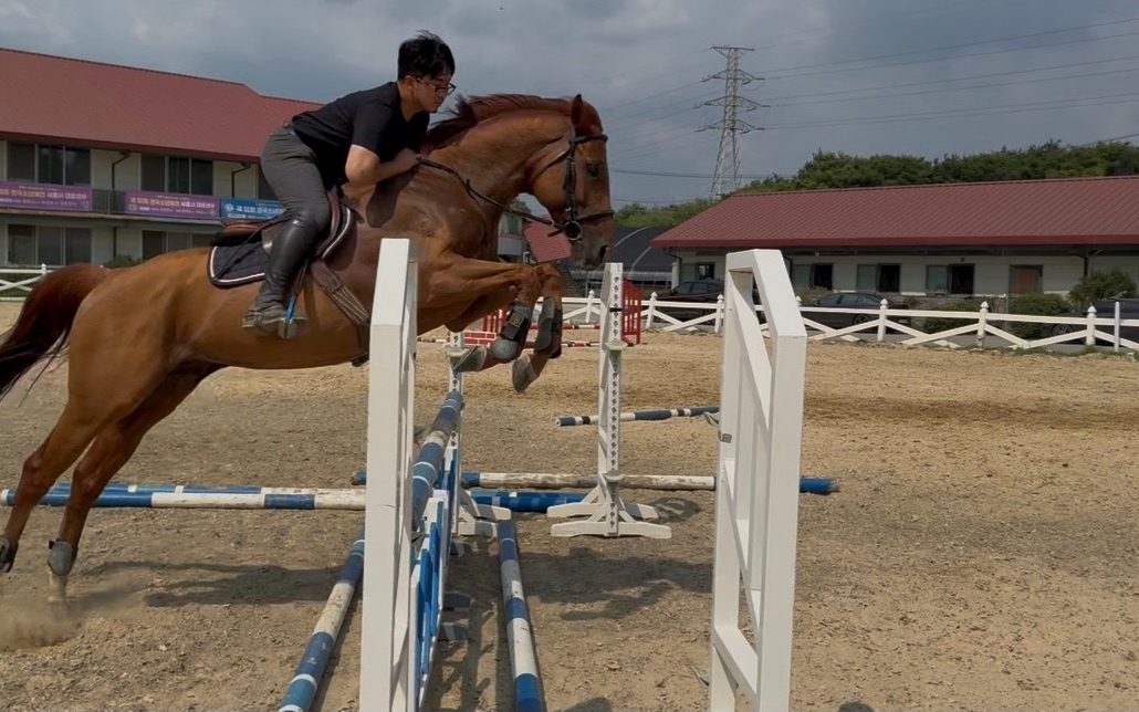 Coach Kim Jinwoo jumping a fence in the outdoor arena at Guri Riding Grounds