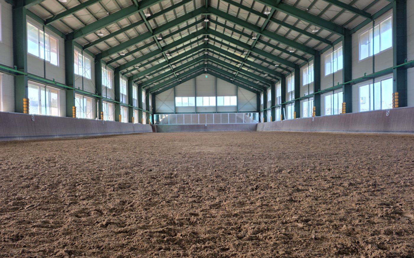 The long indoor arena under a green steel-framed roof