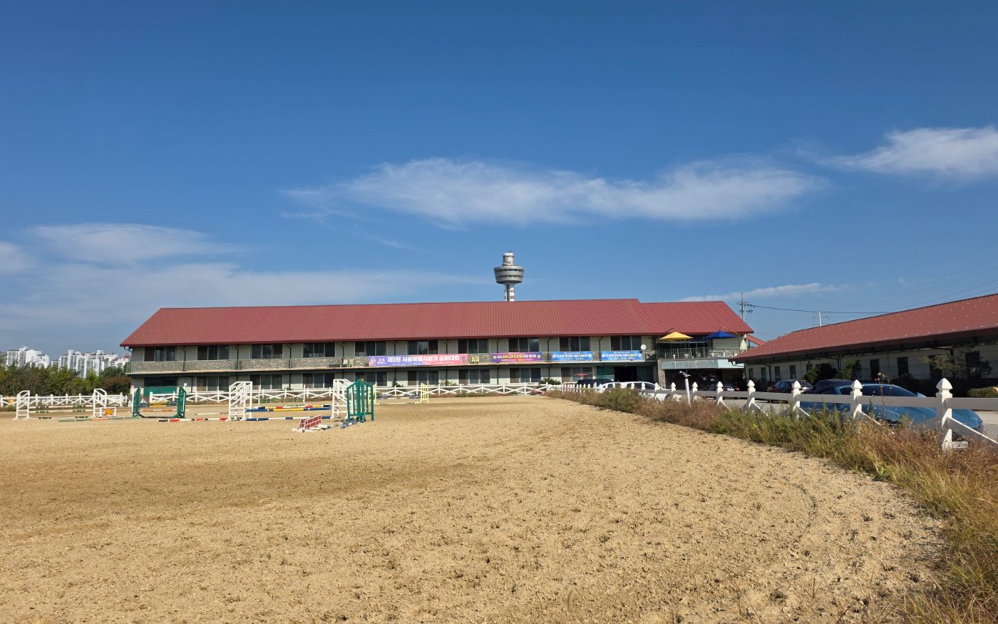 The outdoor arena with jumps set up, the clubhouse and Guri Tower behind